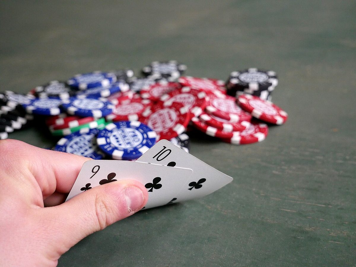 A player holds two cards over a pile of poker chips
