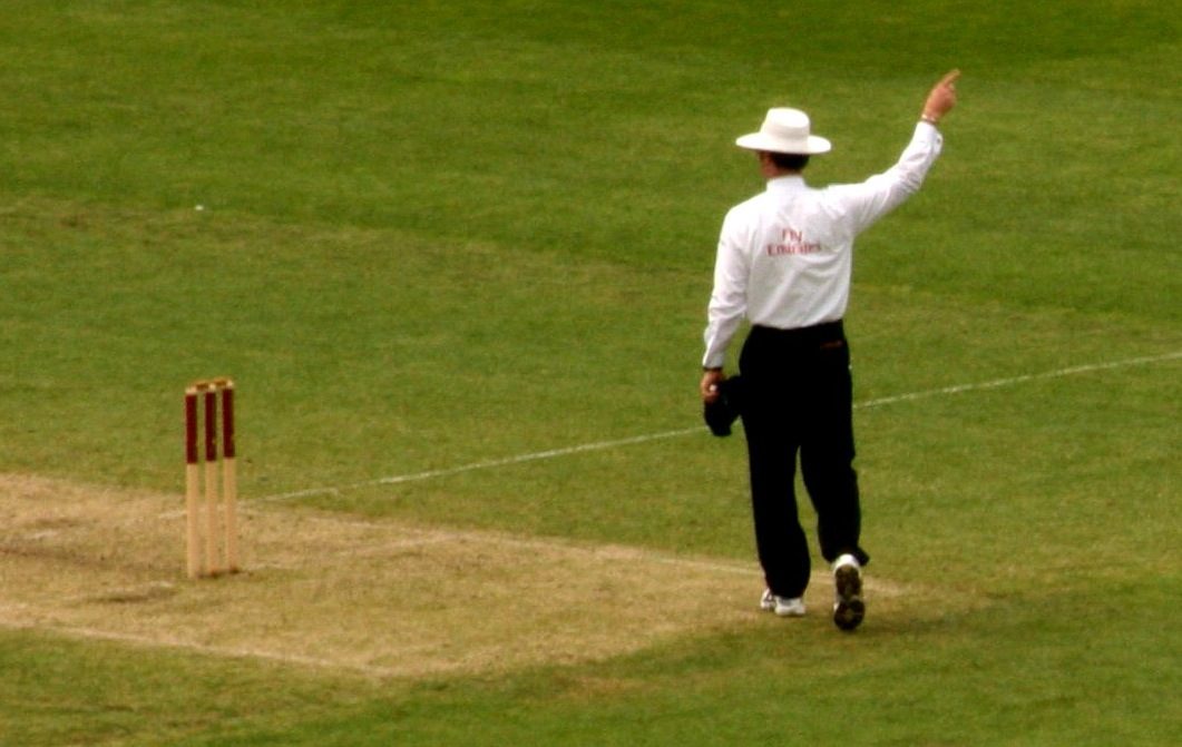 A cricket umpire signals beside the stumps